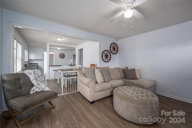 living area with a textured ceiling, ceiling fan, dark wood finished floors, and baseboards