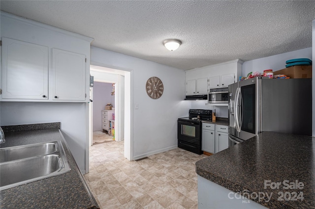 kitchen featuring appliances with stainless steel finishes, dark countertops, a sink, and white cabinets