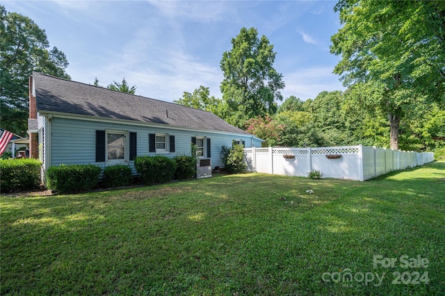 view of front of house with roof with shingles, a front yard, and fence