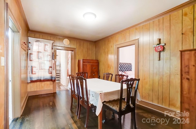 dining room with wooden walls, crown molding, and dark wood-type flooring