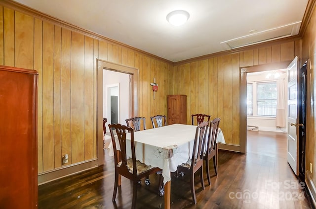 dining space featuring dark hardwood / wood-style floors, ornamental molding, and wooden walls