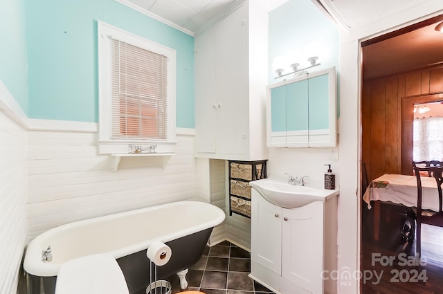 bathroom with vanity, crown molding, tile patterned floors, wooden walls, and a bathtub