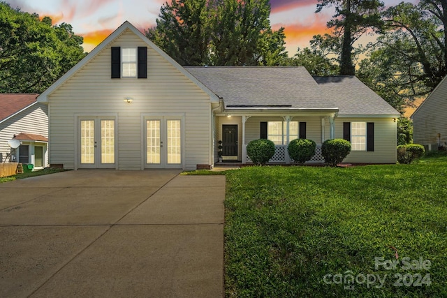 view of front facade with french doors and a lawn