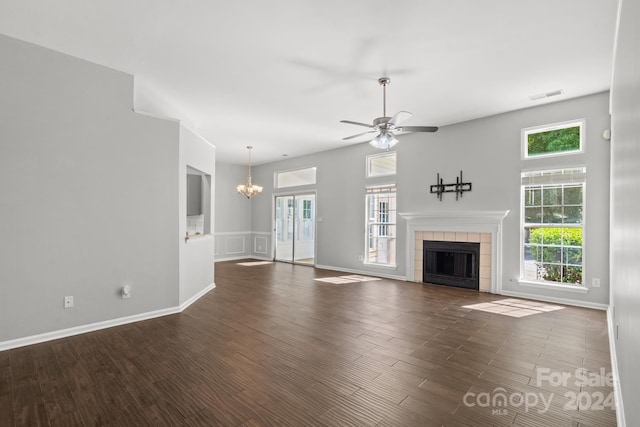 unfurnished living room with plenty of natural light, a tiled fireplace, and dark wood-type flooring