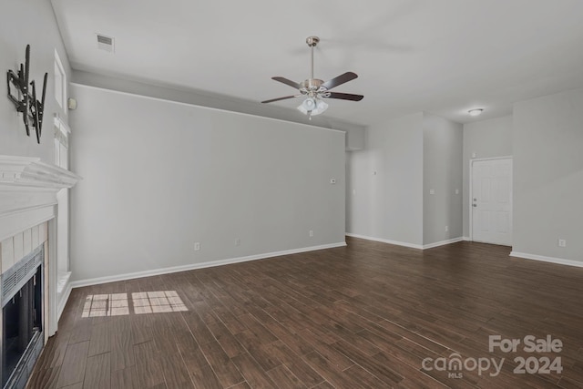 unfurnished living room featuring ceiling fan, a tiled fireplace, and wood-type flooring