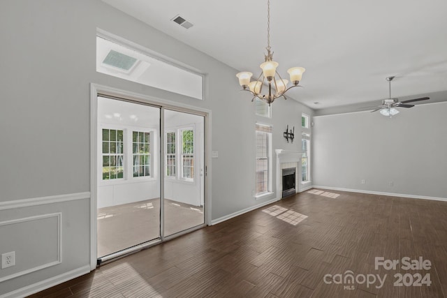 unfurnished living room featuring ceiling fan with notable chandelier and dark hardwood / wood-style floors