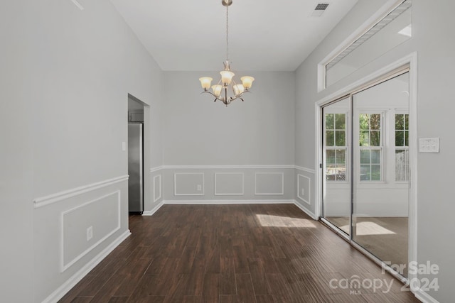 unfurnished dining area featuring a chandelier and dark hardwood / wood-style flooring