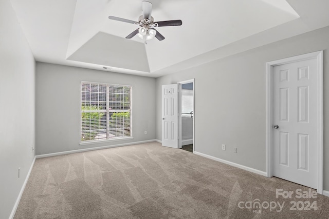 unfurnished bedroom featuring carpet flooring, ceiling fan, and a raised ceiling