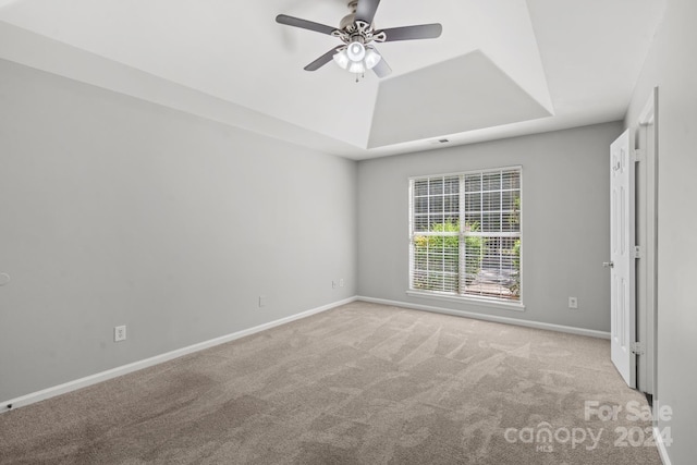 carpeted empty room with ceiling fan and a tray ceiling