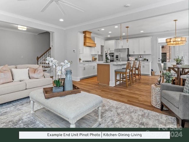 living room featuring ornamental molding, light hardwood / wood-style floors, and ceiling fan with notable chandelier