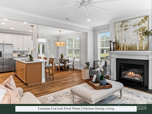 living room with ceiling fan with notable chandelier, light hardwood / wood-style flooring, and crown molding