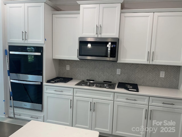 kitchen featuring white cabinets, appliances with stainless steel finishes, and backsplash