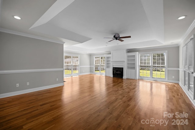 unfurnished living room with crown molding, hardwood / wood-style flooring, ceiling fan, and a tray ceiling