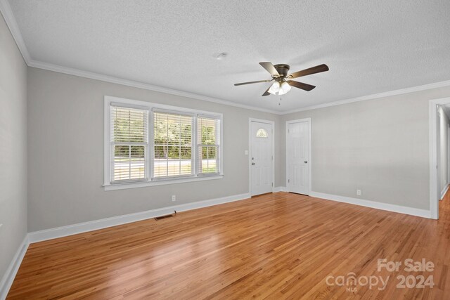 spare room with a textured ceiling, crown molding, ceiling fan, and light wood-type flooring