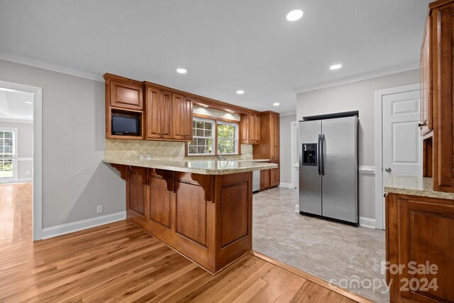 kitchen with stainless steel fridge with ice dispenser, tasteful backsplash, light hardwood / wood-style flooring, and a healthy amount of sunlight