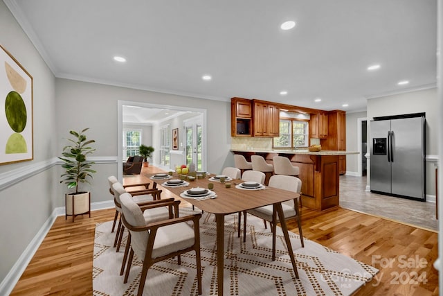 dining room with crown molding, sink, and light wood-type flooring