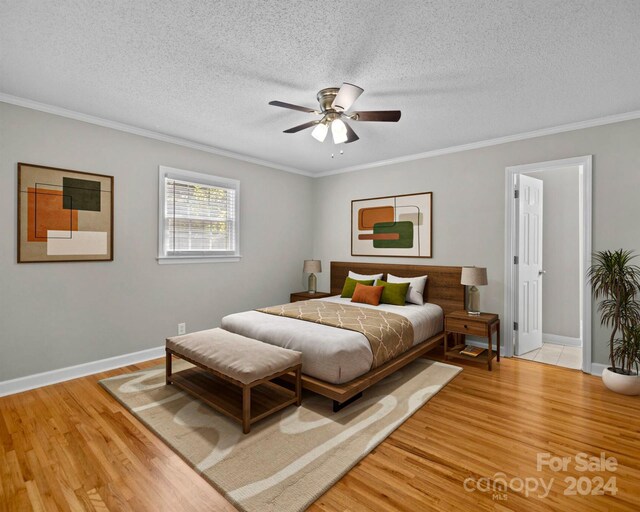 bedroom with ceiling fan, light hardwood / wood-style floors, a textured ceiling, and ornamental molding