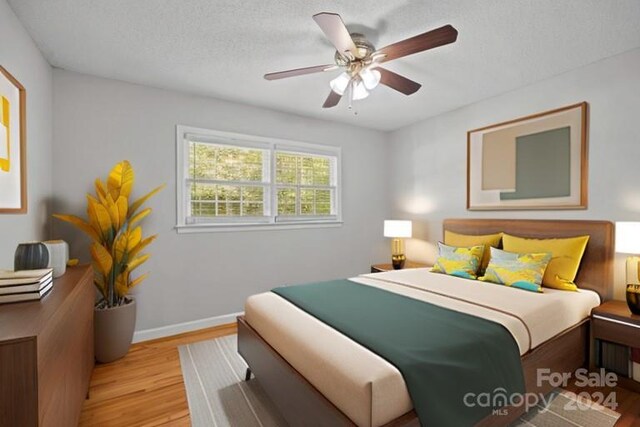 bedroom with light wood-type flooring, ceiling fan, and a textured ceiling