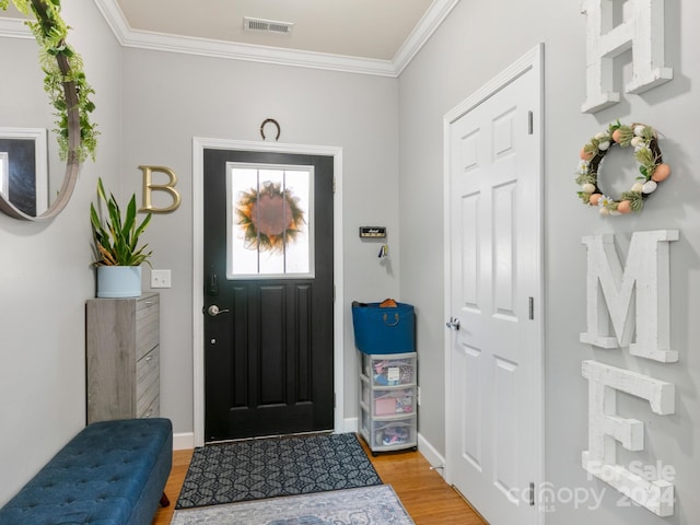 foyer with light wood-type flooring and crown molding