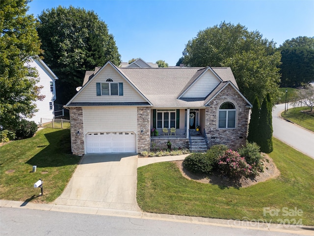 view of front of property featuring a porch, concrete driveway, a garage, stone siding, and a front lawn