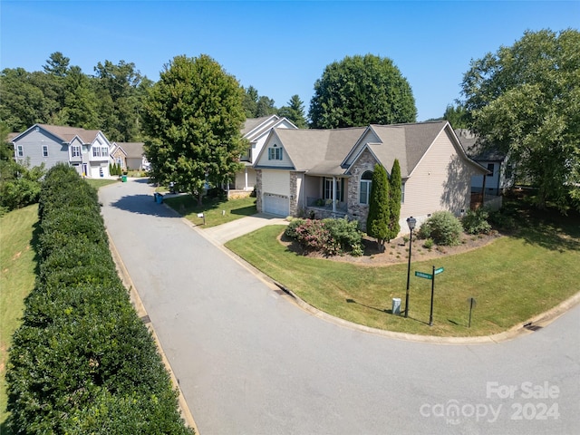 view of front facade with an attached garage, stone siding, concrete driveway, a residential view, and a front lawn