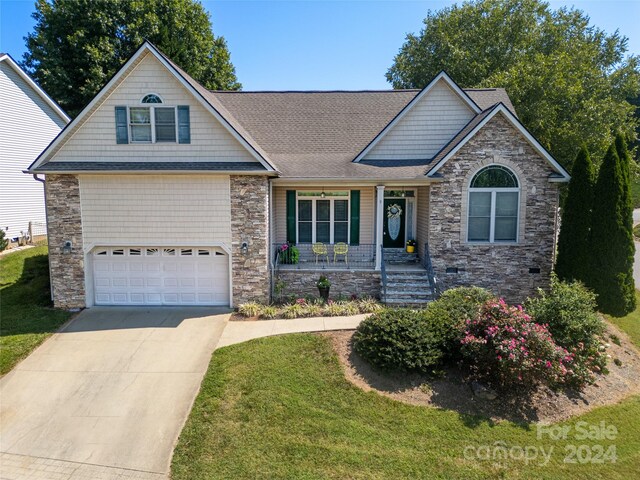 craftsman-style home with a garage, concrete driveway, stone siding, a porch, and a front yard