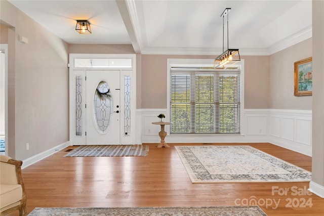 foyer with a wainscoted wall, beamed ceiling, a decorative wall, and wood finished floors