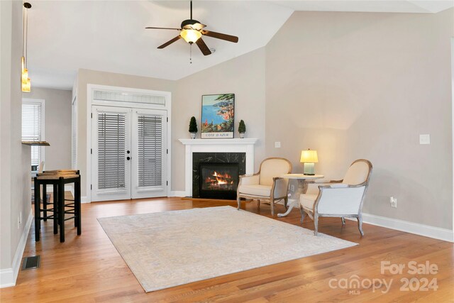 sitting room featuring light wood-type flooring, visible vents, vaulted ceiling, and a premium fireplace