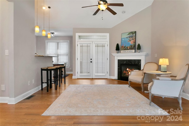 living room featuring baseboards, ceiling fan, wood finished floors, vaulted ceiling, and a high end fireplace