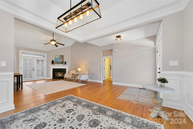 living area with a premium fireplace, vaulted ceiling, ceiling fan, wood finished floors, and baseboards