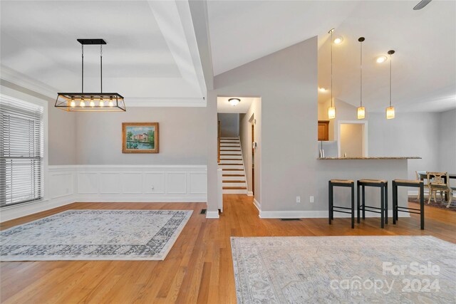 interior space featuring decorative light fixtures, a kitchen breakfast bar, wood finished floors, and freestanding refrigerator