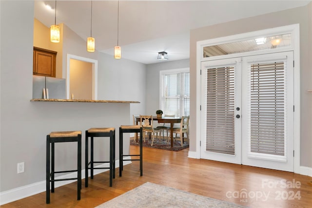 kitchen with light wood-style flooring, a breakfast bar area, brown cabinets, decorative light fixtures, and freestanding refrigerator