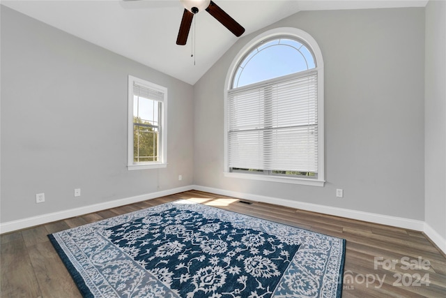 unfurnished room with lofted ceiling, visible vents, a ceiling fan, wood finished floors, and baseboards