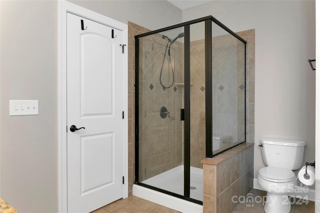 bathroom with a stall shower, tile patterned flooring, and toilet