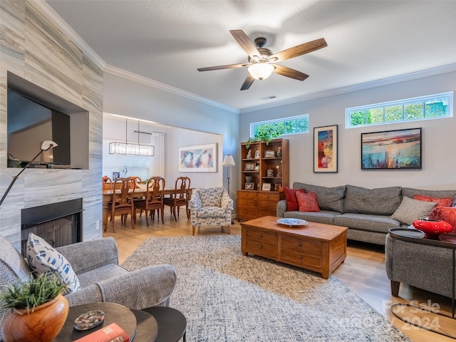 living room featuring light hardwood / wood-style flooring, ceiling fan, ornamental molding, and a tiled fireplace