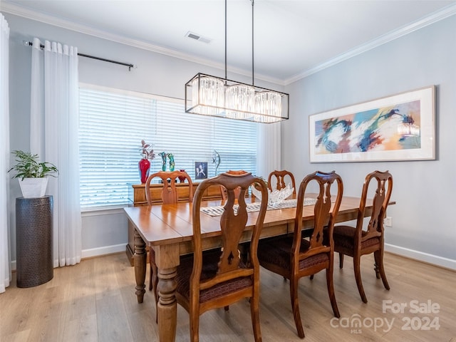 dining area with an inviting chandelier, light hardwood / wood-style flooring, and ornamental molding