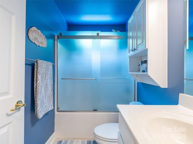 full bathroom featuring tile patterned flooring, toilet, bath / shower combo with glass door, and vanity