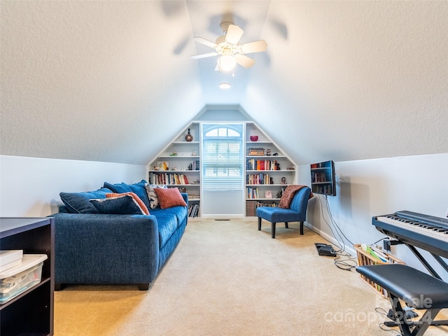 living area with ceiling fan, vaulted ceiling, light colored carpet, and built in shelves