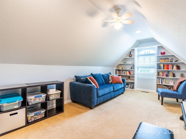 sitting room with ceiling fan, lofted ceiling, light colored carpet, and built in shelves