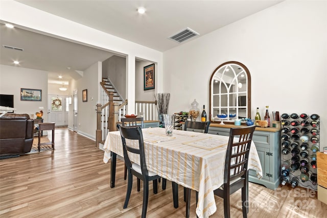 dining space featuring visible vents, stairs, and light wood-style floors