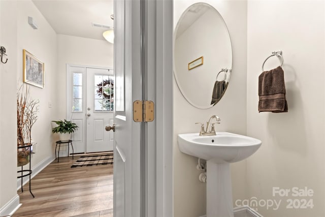 bathroom with a sink, baseboards, wood finished floors, and visible vents