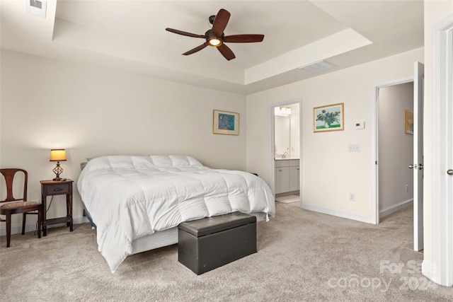 bedroom featuring light colored carpet, ceiling fan, a raised ceiling, and connected bathroom