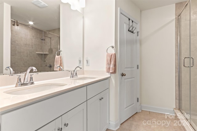 bathroom featuring vanity, a shower with shower door, and tile patterned flooring