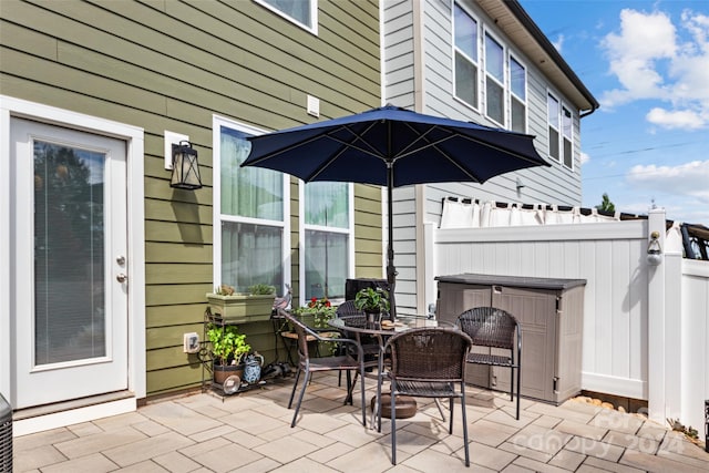 view of patio with fence, outdoor dining space, and a jacuzzi