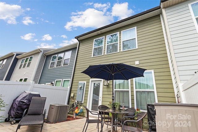 back of property with central AC unit and a patio