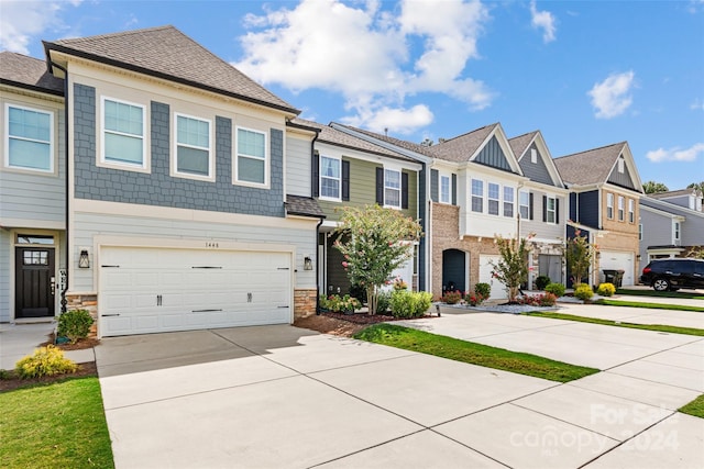 view of property with a garage, stone siding, a residential view, and concrete driveway