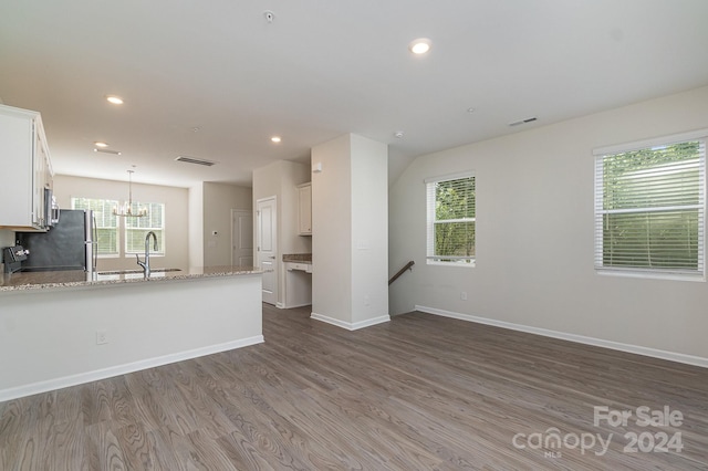 kitchen featuring a wealth of natural light, white cabinetry, light stone counters, and wood-type flooring