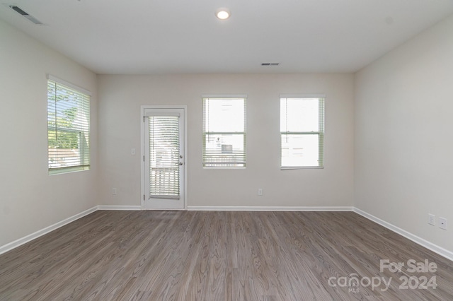 empty room with hardwood / wood-style floors and a healthy amount of sunlight