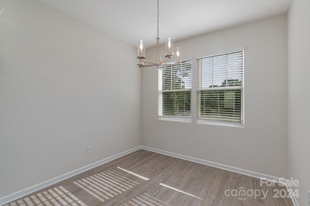 empty room with hardwood / wood-style flooring and a notable chandelier