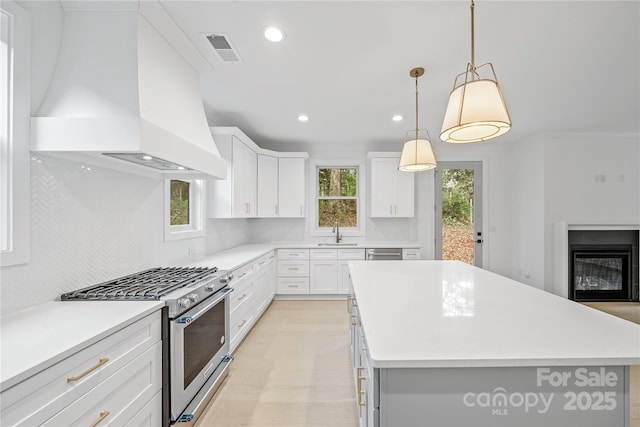 kitchen with a center island, stainless steel appliances, white cabinetry, and premium range hood